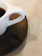 Close-up of a handmade stoneware cup filled with coffee, resting on a wooden table.
