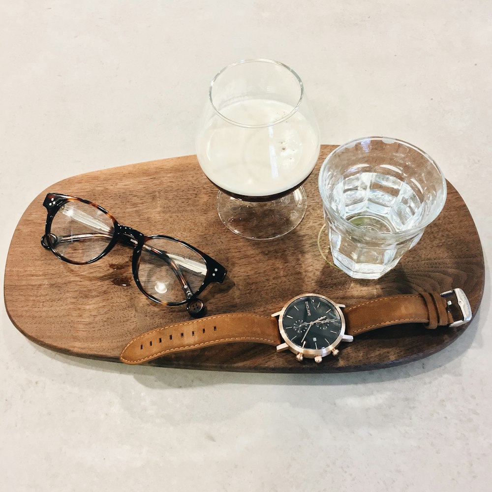 a wooden tray with glasses and a watch on it