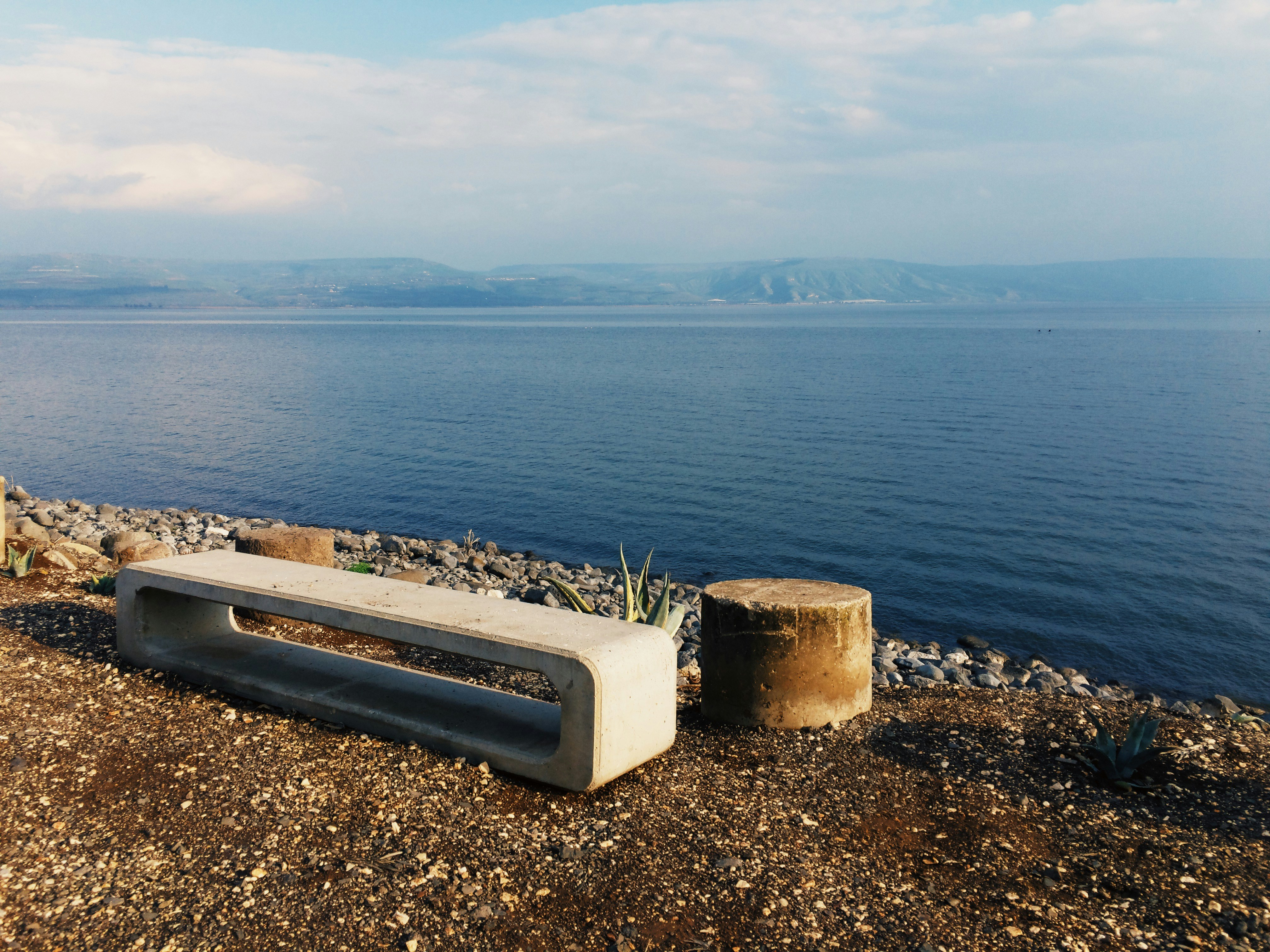 a concrete bench sitting on top of a rocky beach