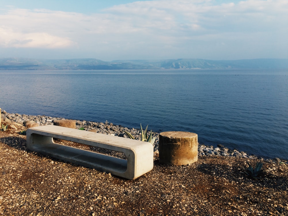 a concrete bench sitting on top of a rocky beach