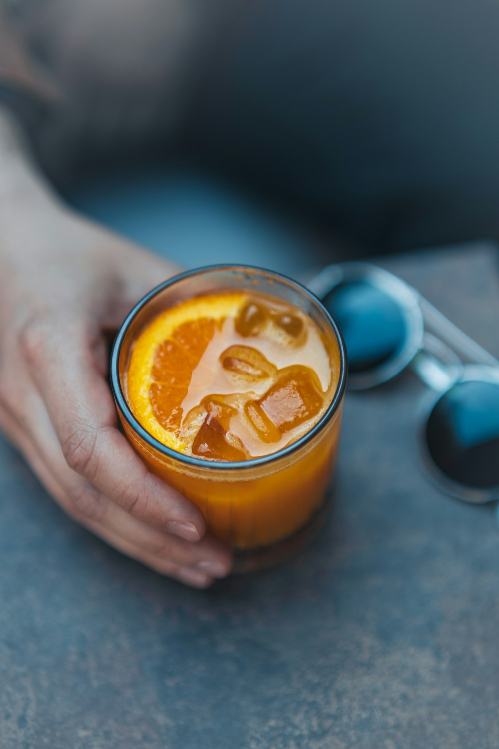 a person holding a glass of orange juice