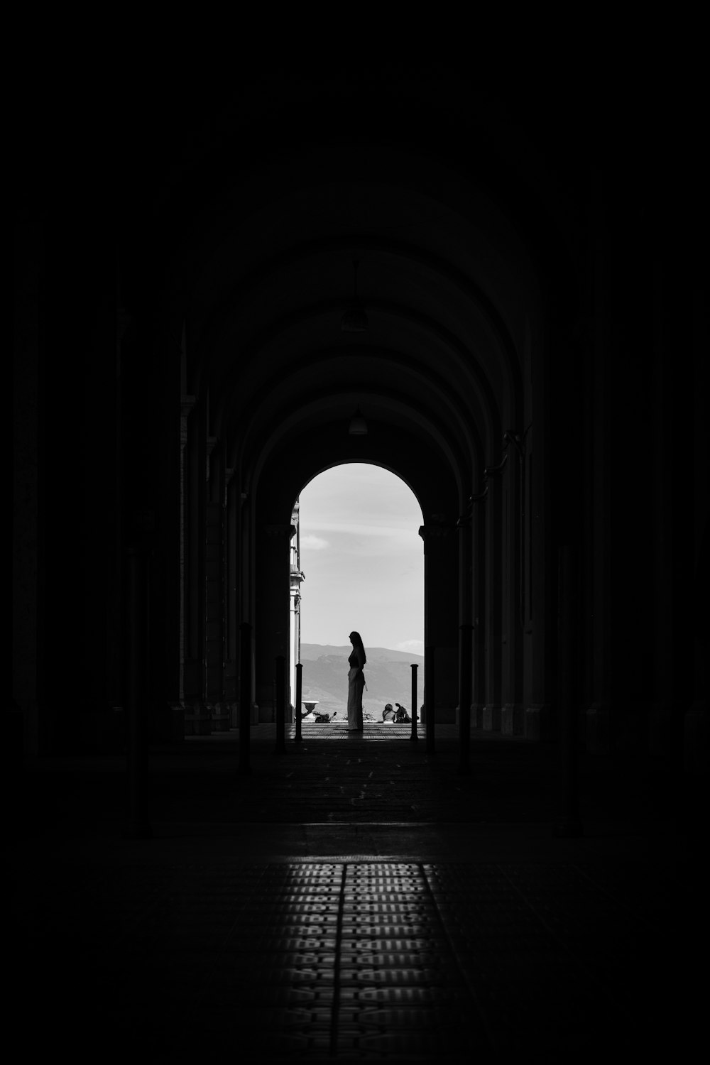 a black and white photo of a person standing in a tunnel