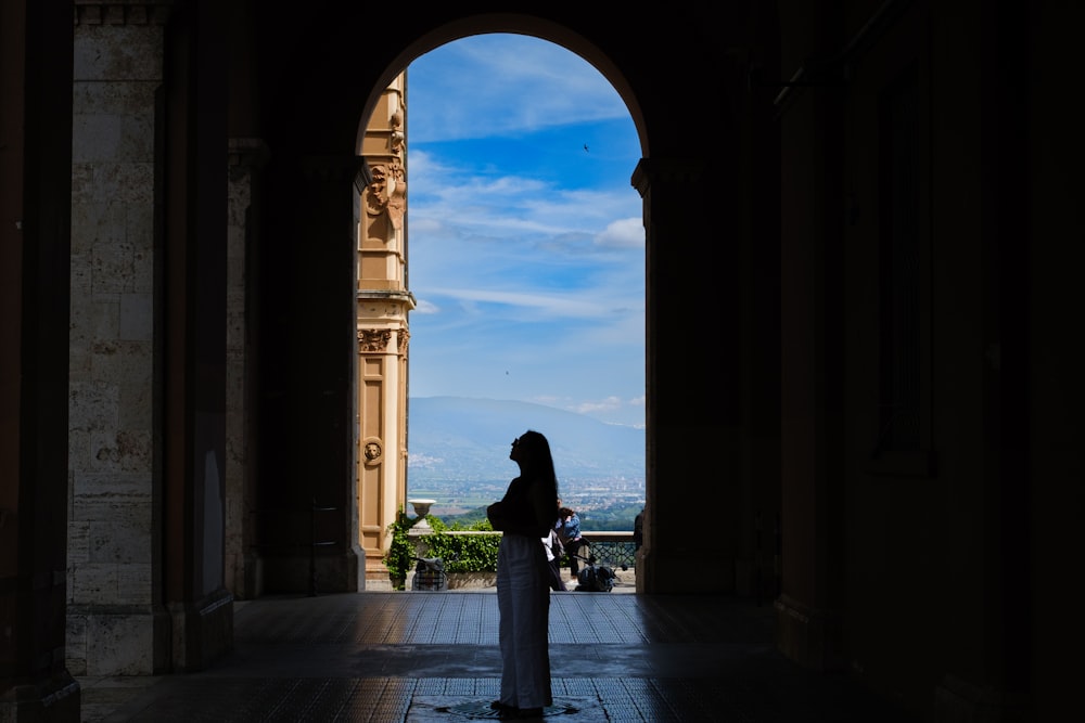 a woman standing in an archway with a view of a city