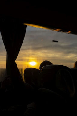 A welcoming driver helping a passenger into a clean and comfortable vehicle at sunset