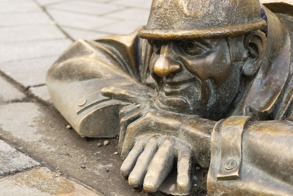 a bronze statue of a man laying on the ground