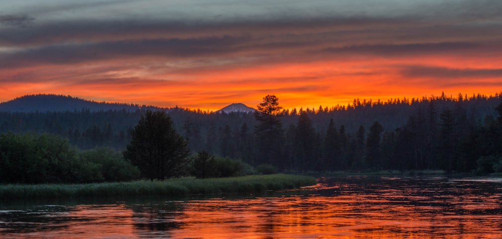 a sunset over a river with a mountain in the background