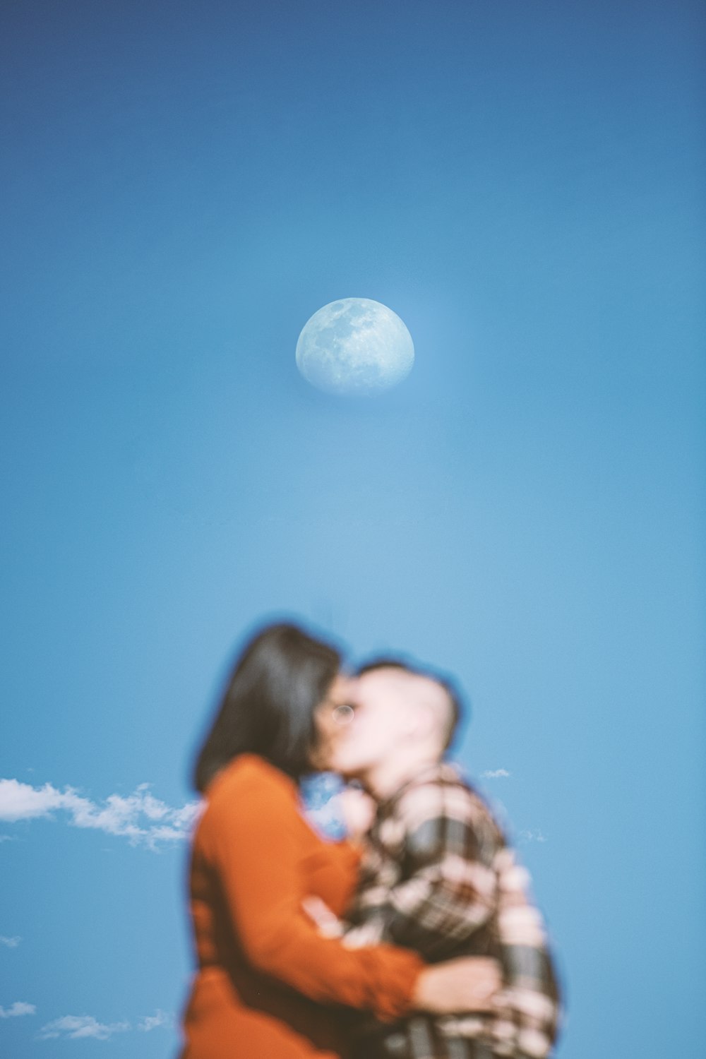 a man and a woman kissing under a full moon