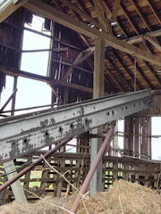 Historic barn with weathered wood beams and vintage farming tools displayed inside.