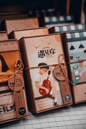 Several packaged goods, possibly books or boxes of stationery, are neatly arranged. Each package is wrapped with a string, and one prominently features an illustration of a person playing the guitar. The text on the package includes both English and Chinese characters.