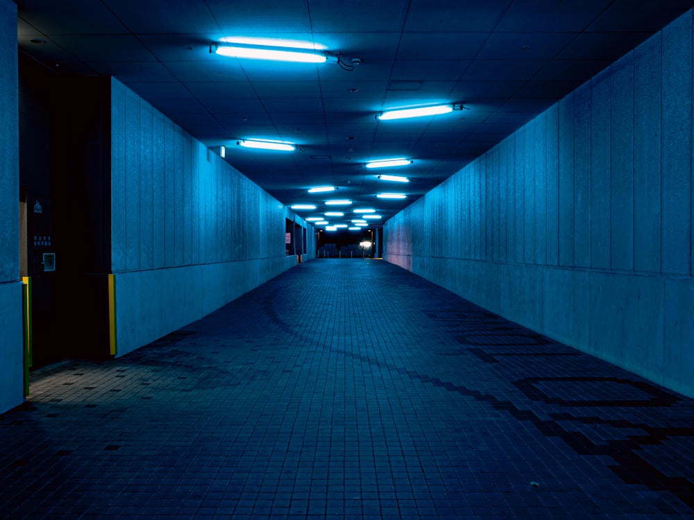 Un lungo corridoio buio con luci blu sul soffitto