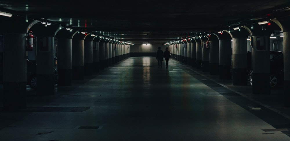 a person walking down a dark hallway in a parking garage