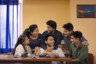 A candid shot of a small group Bible study gathered around a table, sharing and smiling in deep conversation.