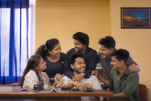 A diverse group of people smiling and interacting around a table.