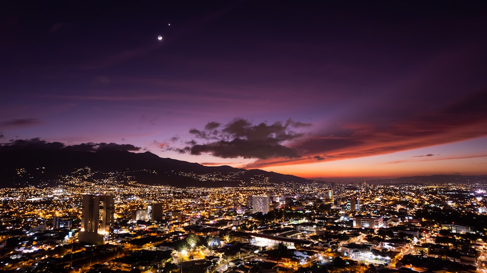 a view of a city at night with the moon in the sky