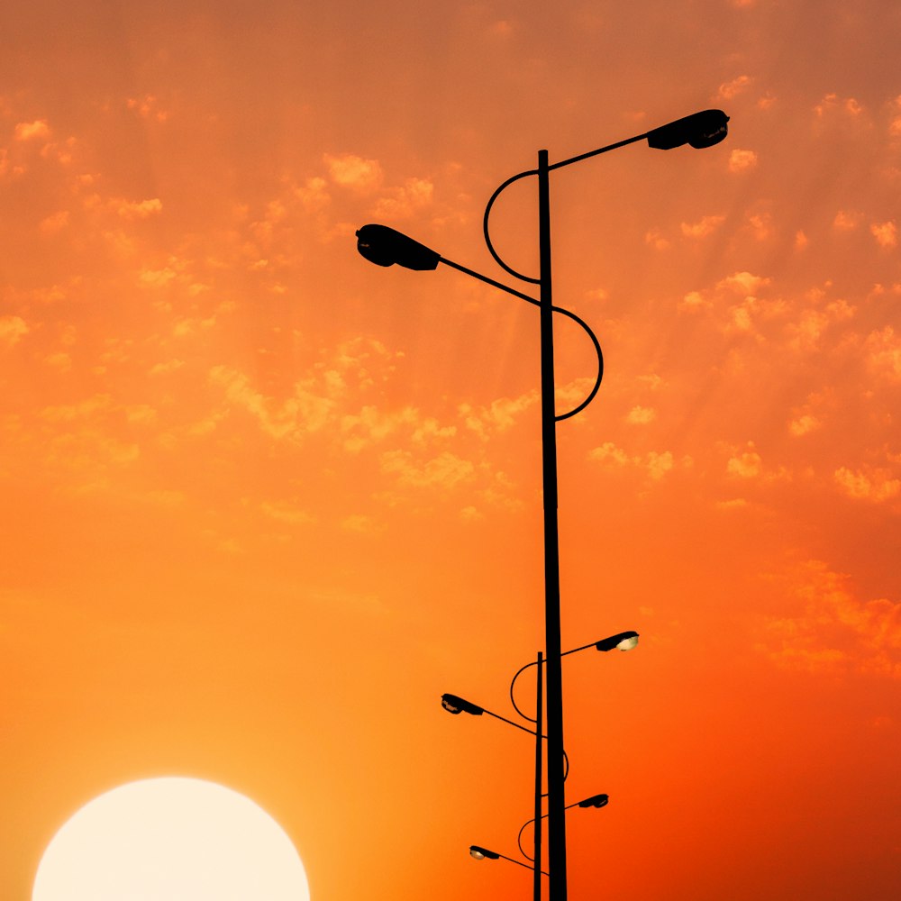 the sun is setting behind a street light