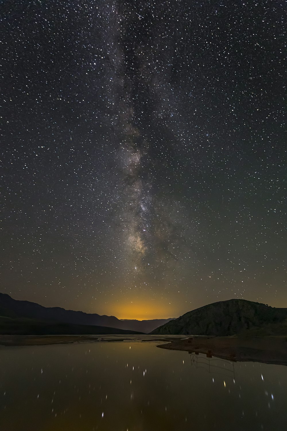 the night sky is filled with stars above a lake