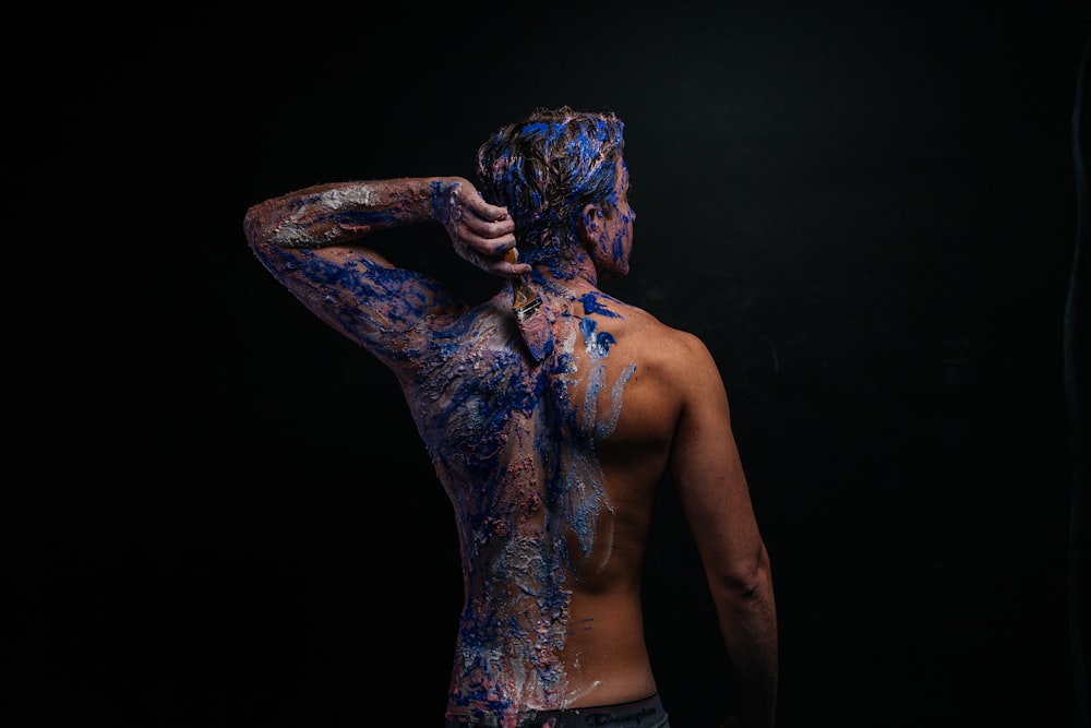 a man with his back to the camera covered in blue paint
