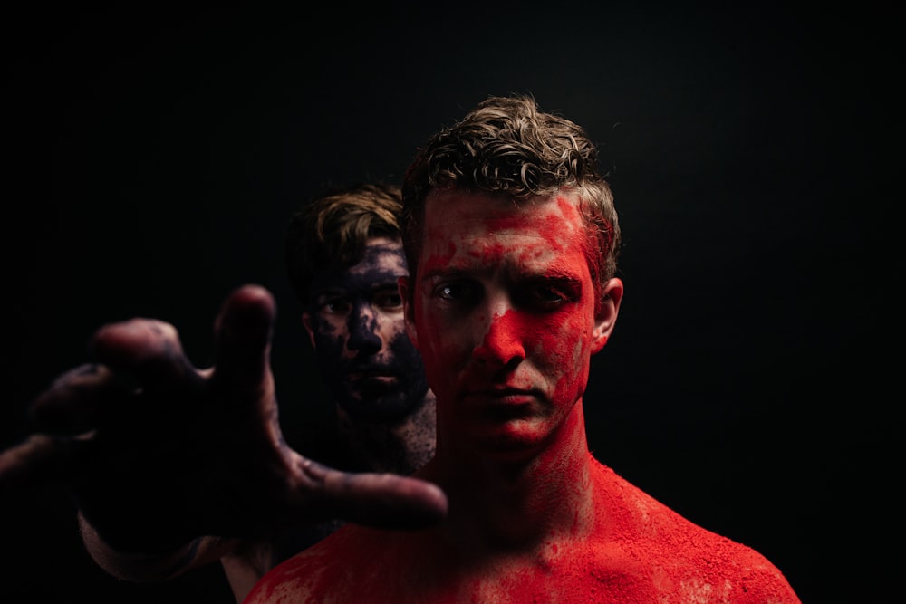 a man with red paint on his face and hands