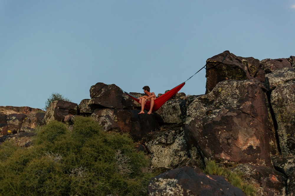 Un uomo seduto sulla cima di una grande roccia
