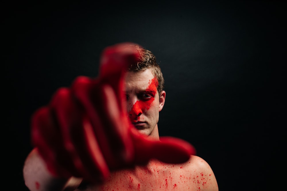 a man with red paint on his face and hands
