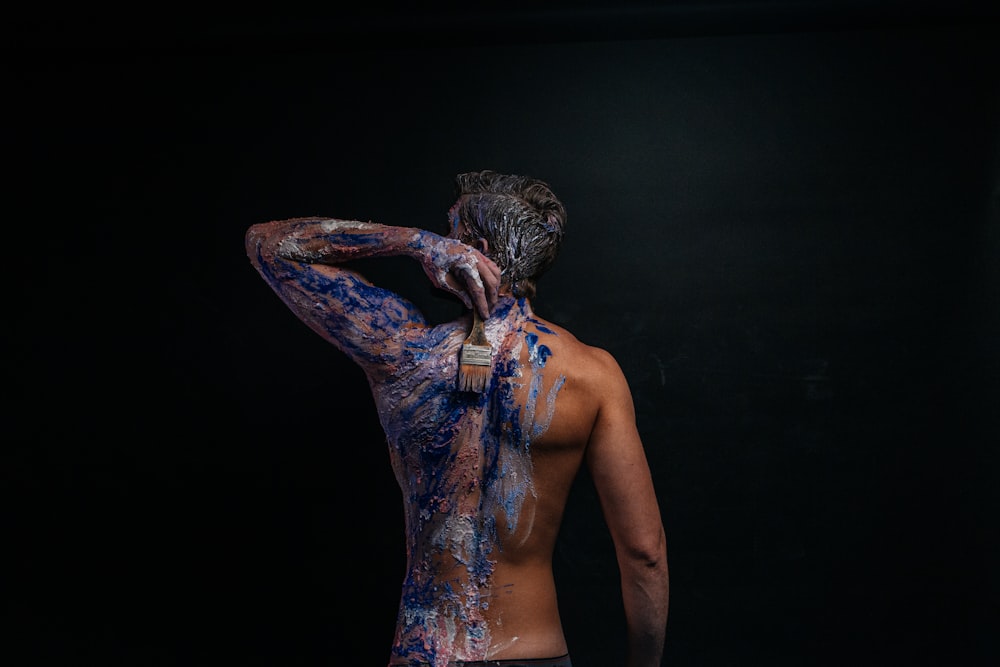 a man with his back to the camera covered in blue paint