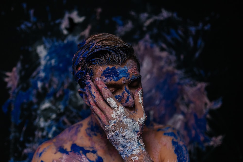 a man covered in blue and white paint covering his face