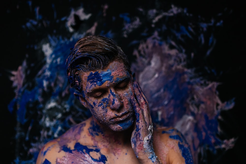 a man covered in blue paint covering his face