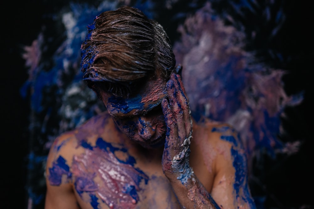 a man covered in blue and purple paint covering his face