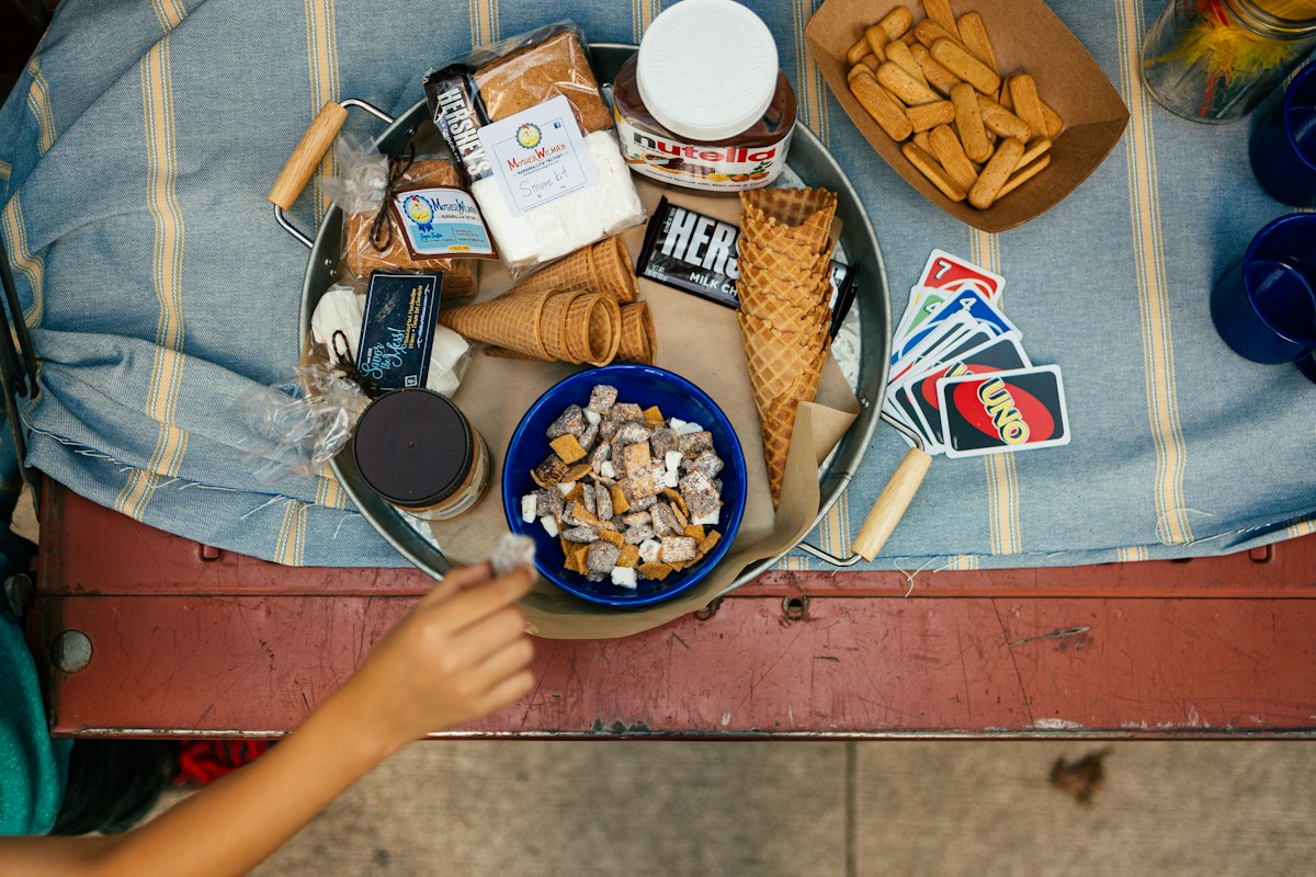 A picnic table with a plate of assorted tailgate food, including burgers, chips, and dips, ideal for tailgate party planning.
