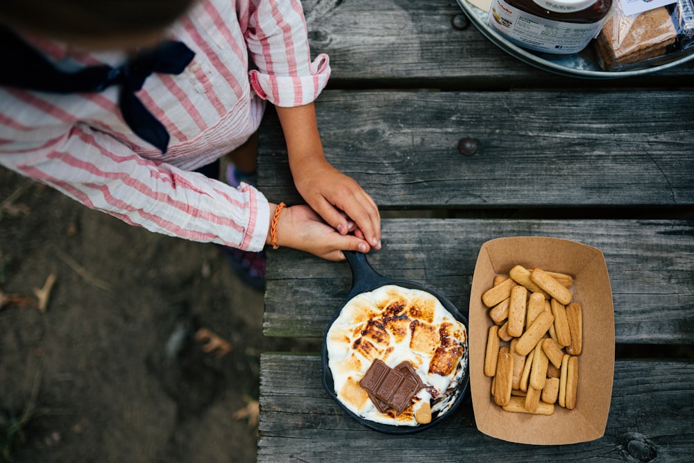 a person sitting at a picnic table with a plate of food