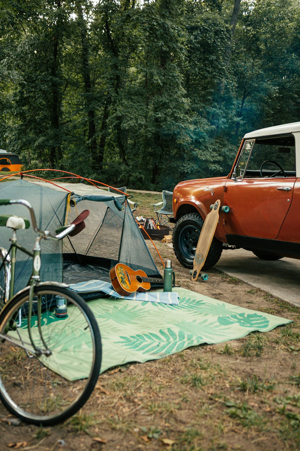 an orange car parked next to a tent and a bicycle