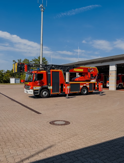 A bright red fire truck parked proudly in front of the Drenje fire station on a sunny day