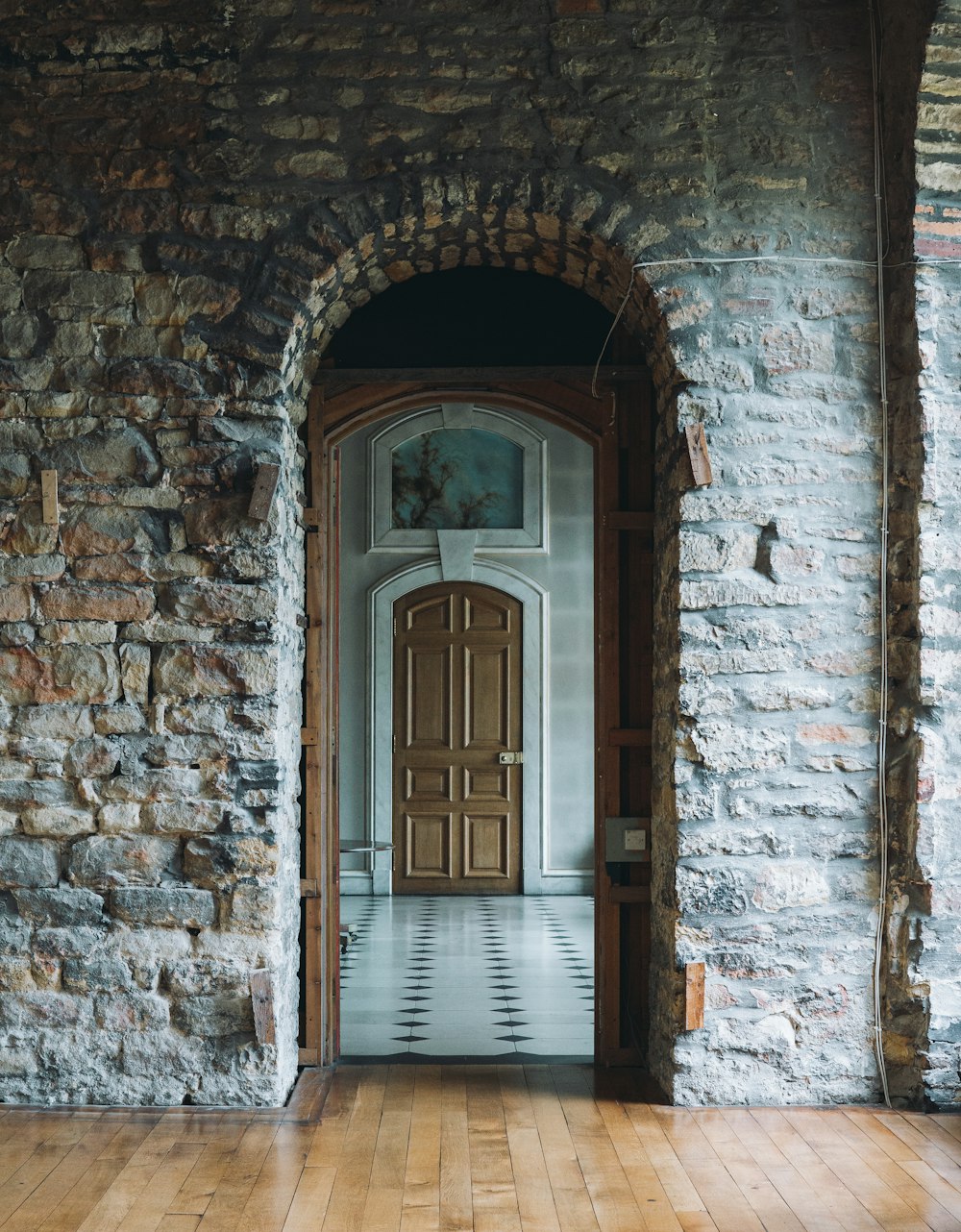 a wooden door in a stone wall with a checkered floor