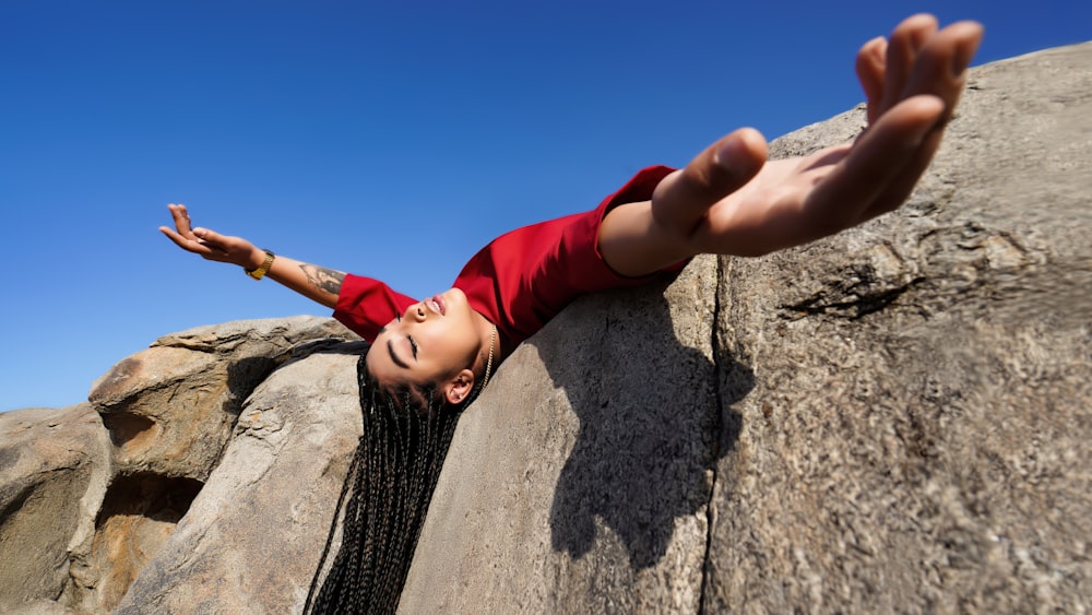 a young girl climbing up the side of a rock
