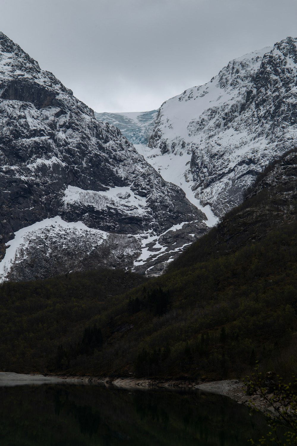 a mountain range covered in snow next to a body of water