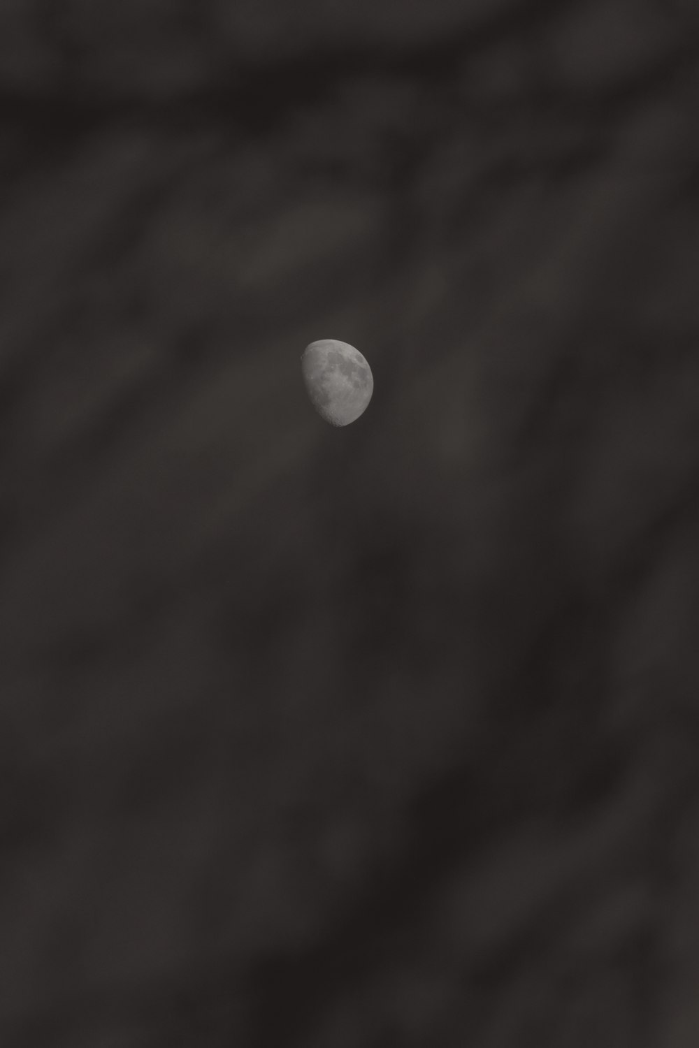 the moon is seen through the clouds in black and white