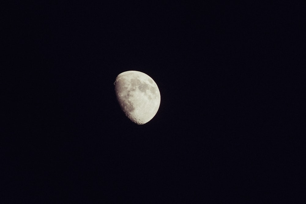 a half moon is seen in the dark sky