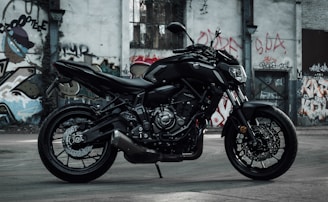 A close-up of a sleek motorcycle parked against a graffiti-covered wall.
