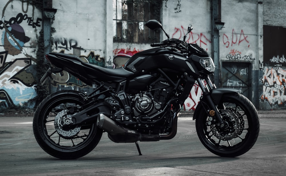 a black motorcycle parked in front of a graffiti covered building