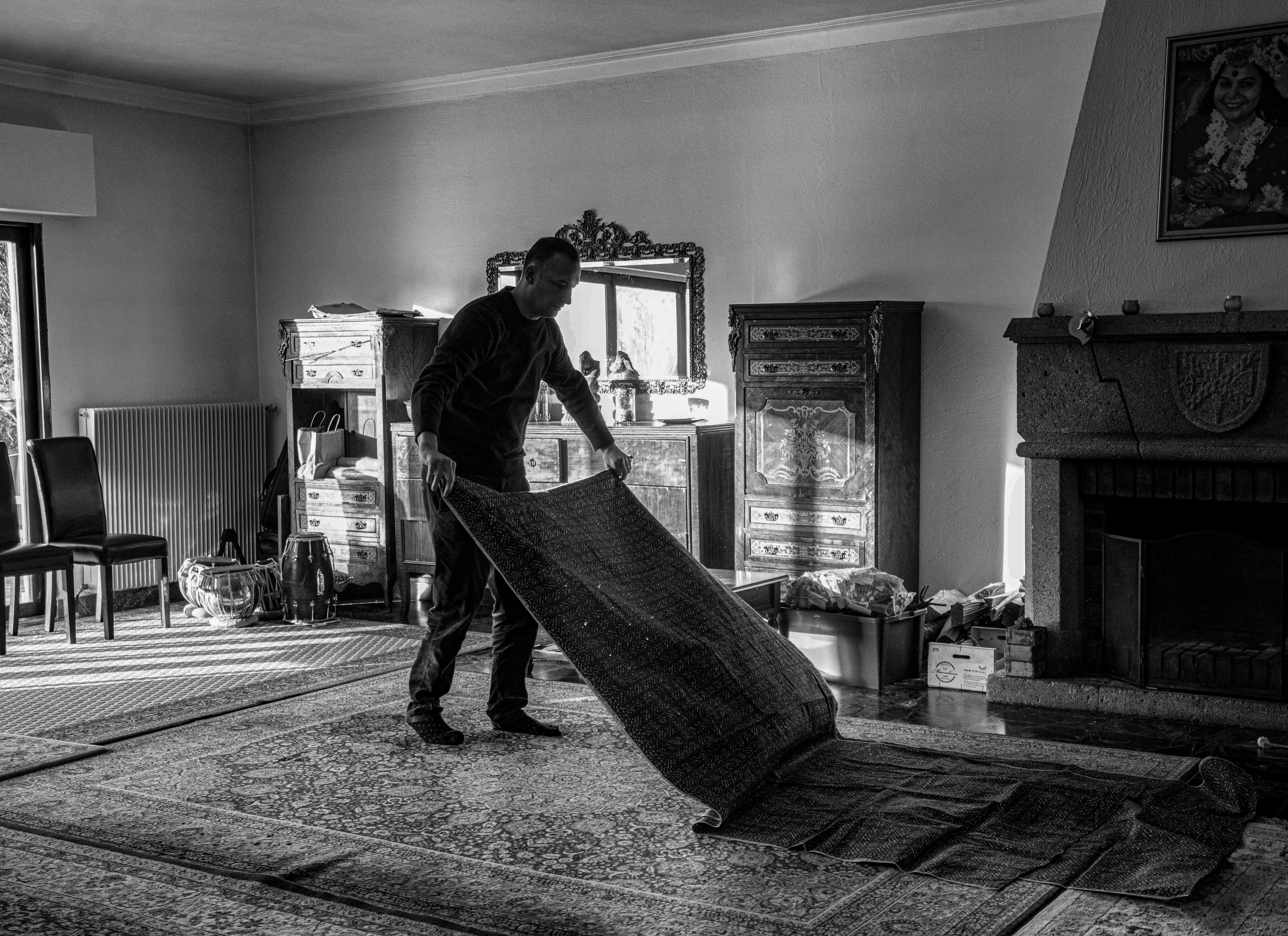 a black and white photo of a man moving a rug