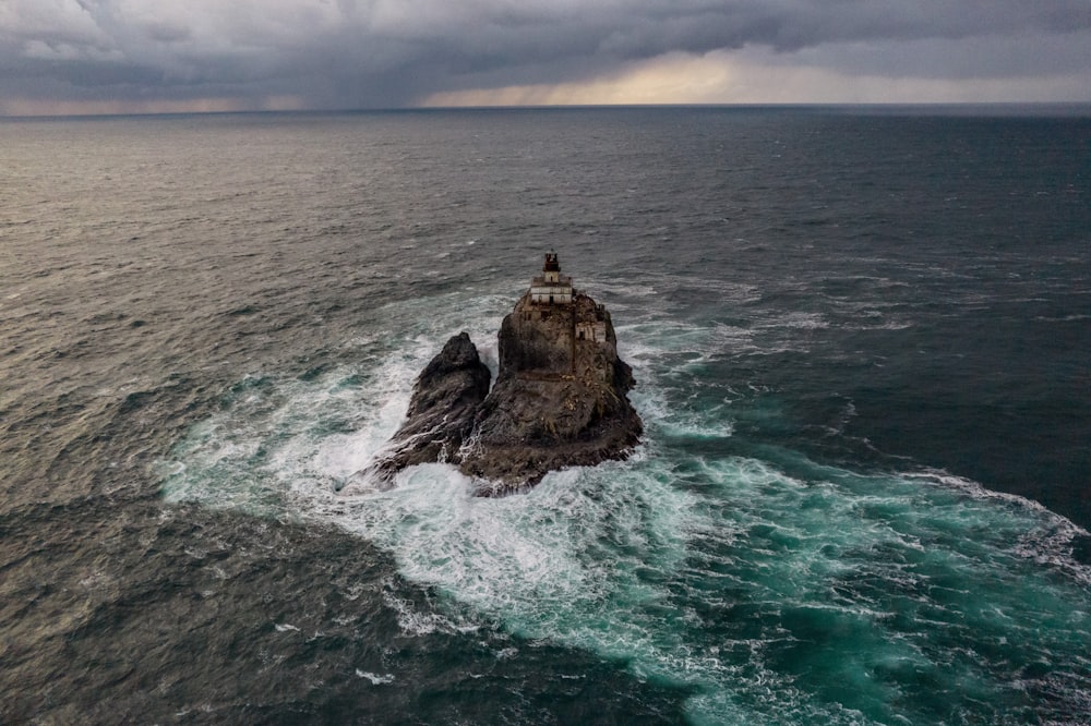 a lighthouse on a rock in the middle of the ocean