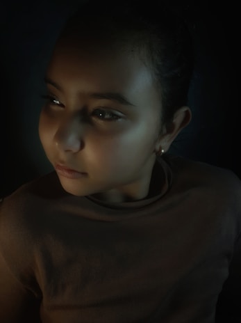 A softly lit portrait of a child in stylish, timeless clothing against a neutral backdrop.