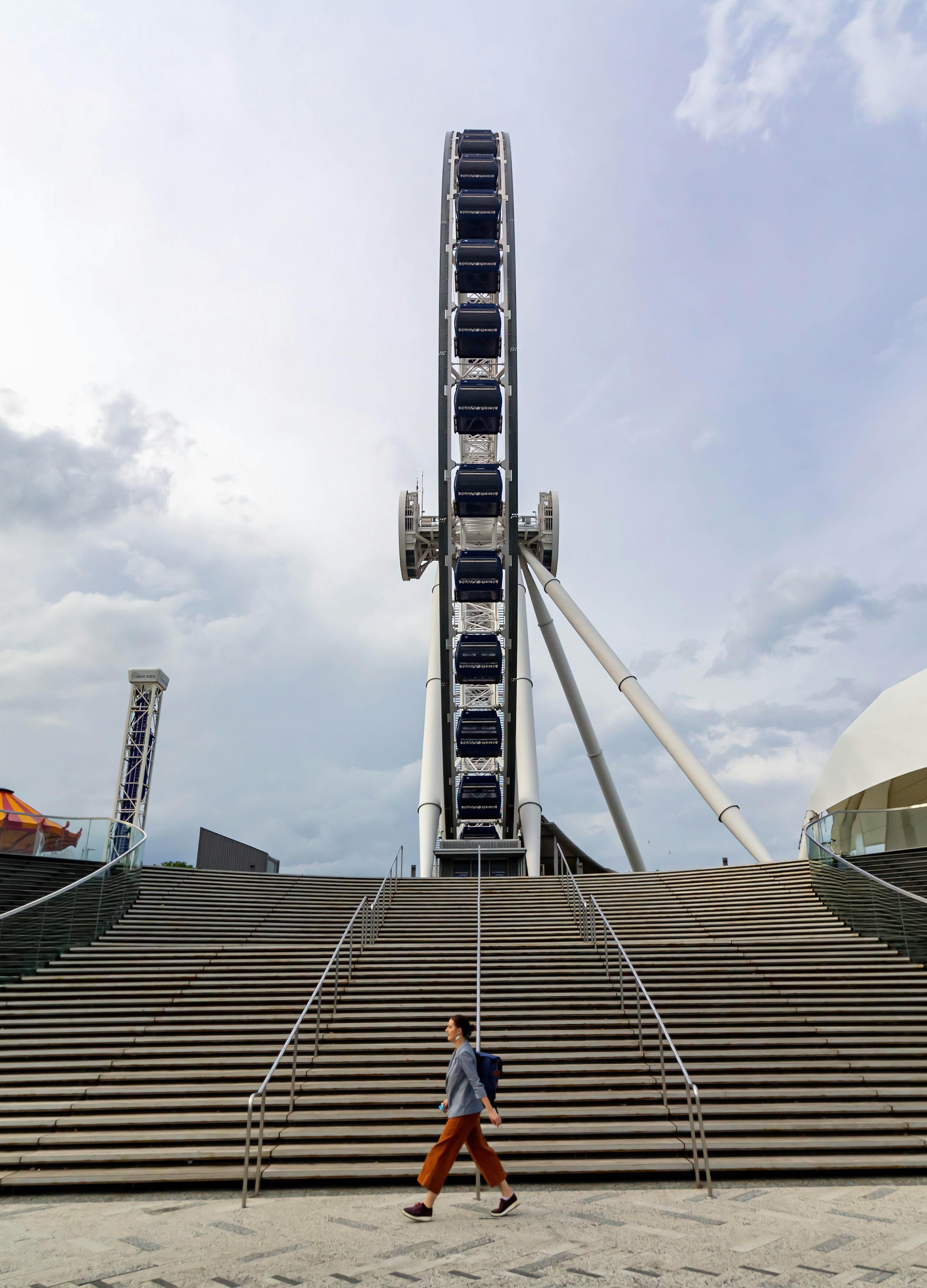 a man walking past a giant ferris wheel