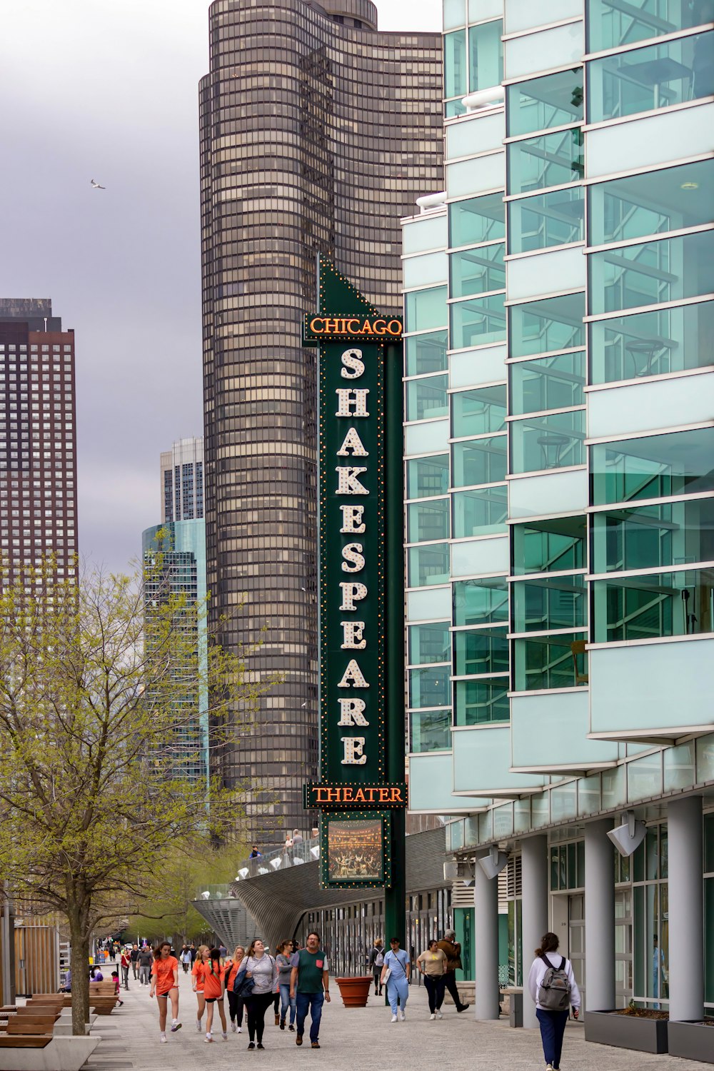 a group of people walking down a street next to tall buildings