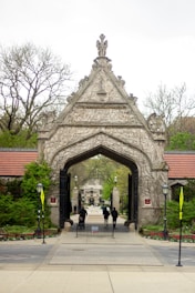 a group of people walking under a stone archway