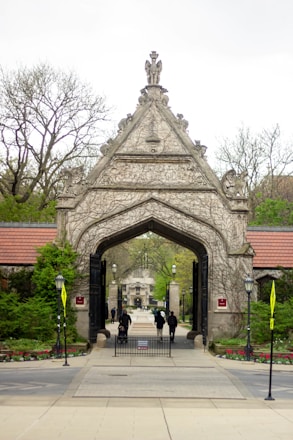 a group of people walking under a stone archway