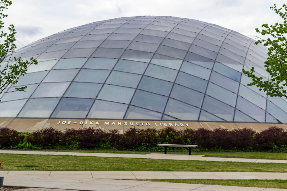 a large glass building with a bench in front of it