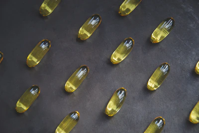 Glossy softgel capsules filled with golden oil against a clean white background.