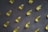 A collection of yellow capsules neatly arranged on a dark, textured surface. Each capsule is oblong and translucent, containing an oily liquid.