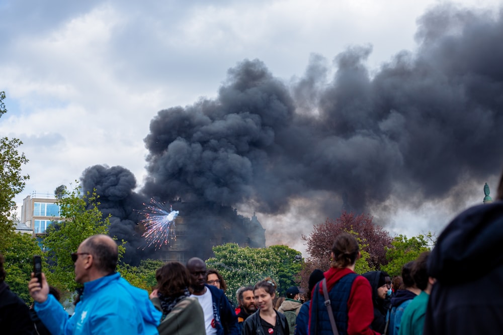 a group of people standing in front of a black cloud of smoke